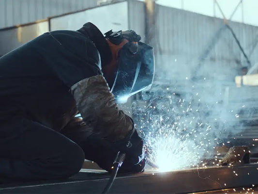 Geübter Industriearbeiter, der Lichtbogenschweißen an der Metallstruktur in der Fabrik durchführt